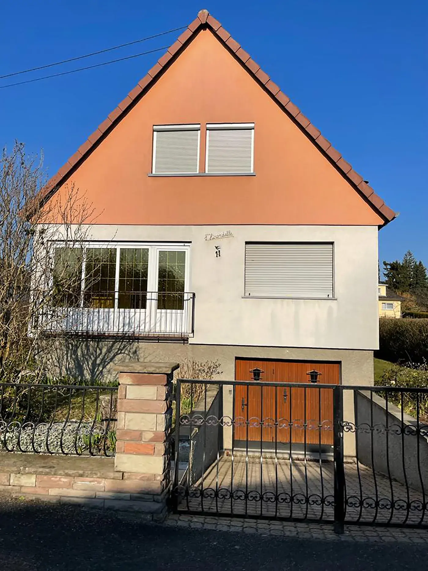 Maison alsacienne avant travaux : petites fenêtres blanches, garage en bois, volets roulants d'origine