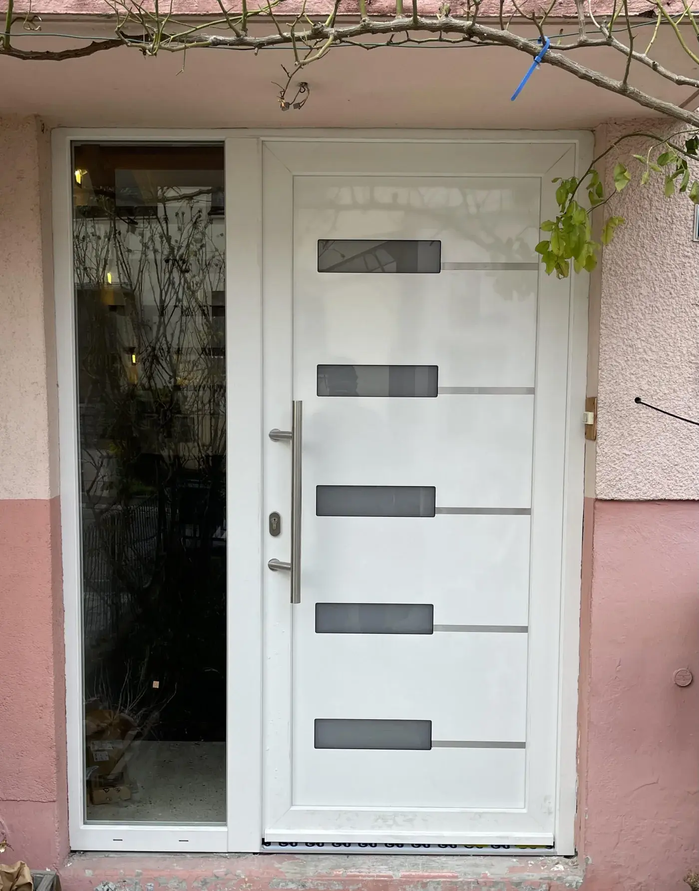 Porte d'entrée PVC blanche à inserts gris posée dans le même tableau