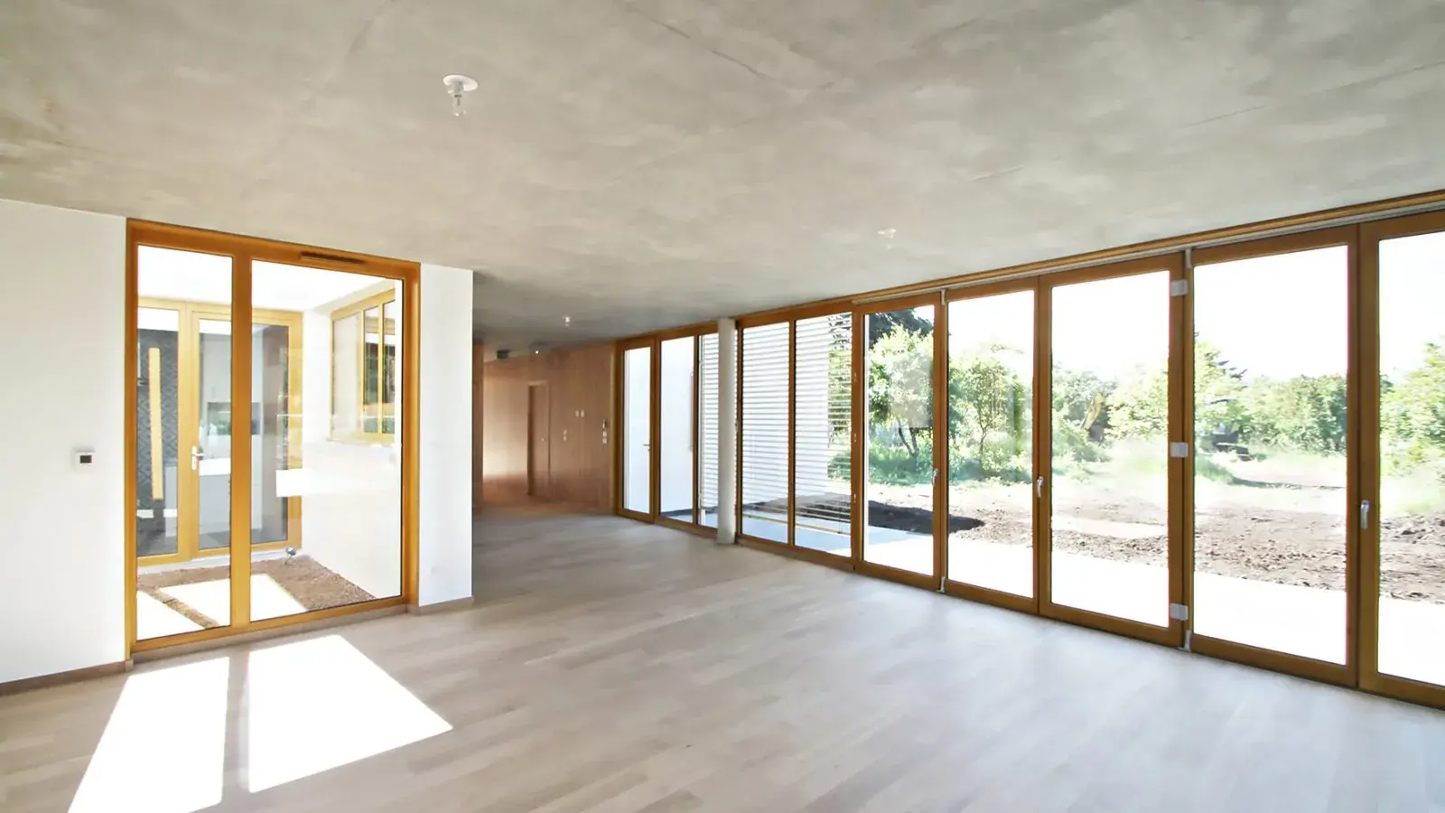 Grande pièce claire avec une baie filante en menuiserie bois sur toute la longueur