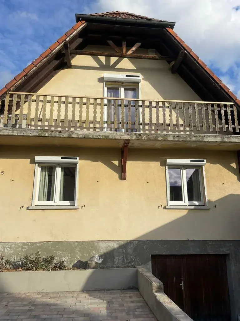 Maison alsacienne crème à balcon de bois et soubassement en grès, fenêtres neuves