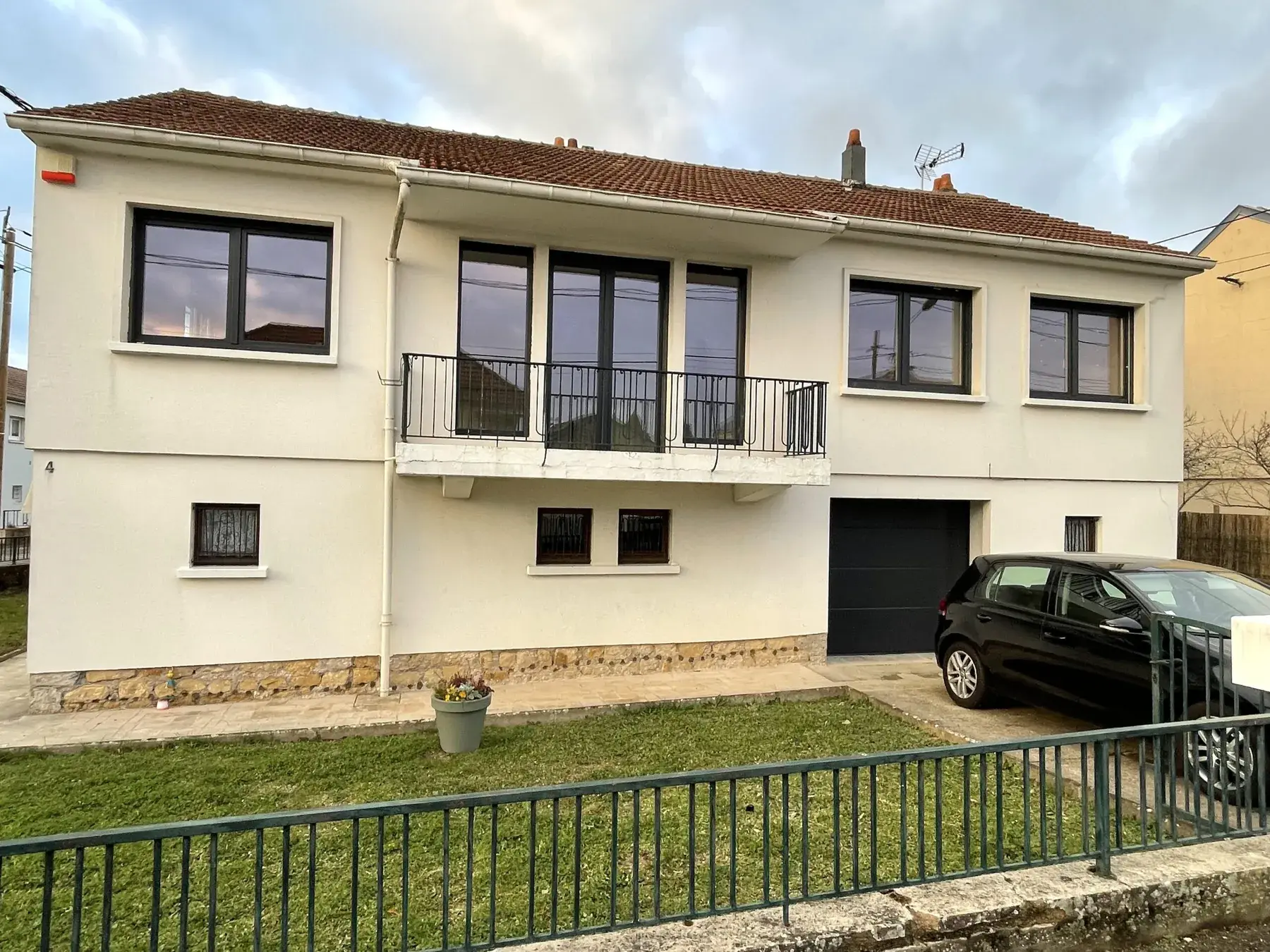 Pavillon des années 60 au crépi jaune avec balcon, menuiseries et garage rénovés