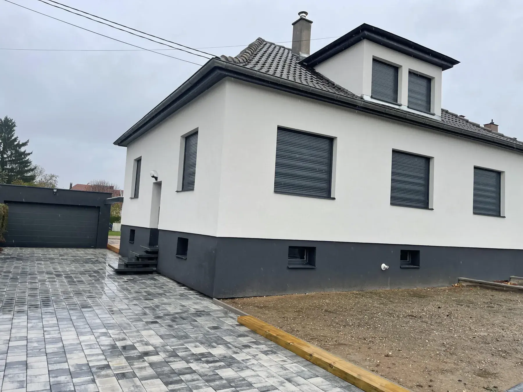 Maison blanche et anthracite avec grande cour pavée, menuiseries et porte de garage neuves