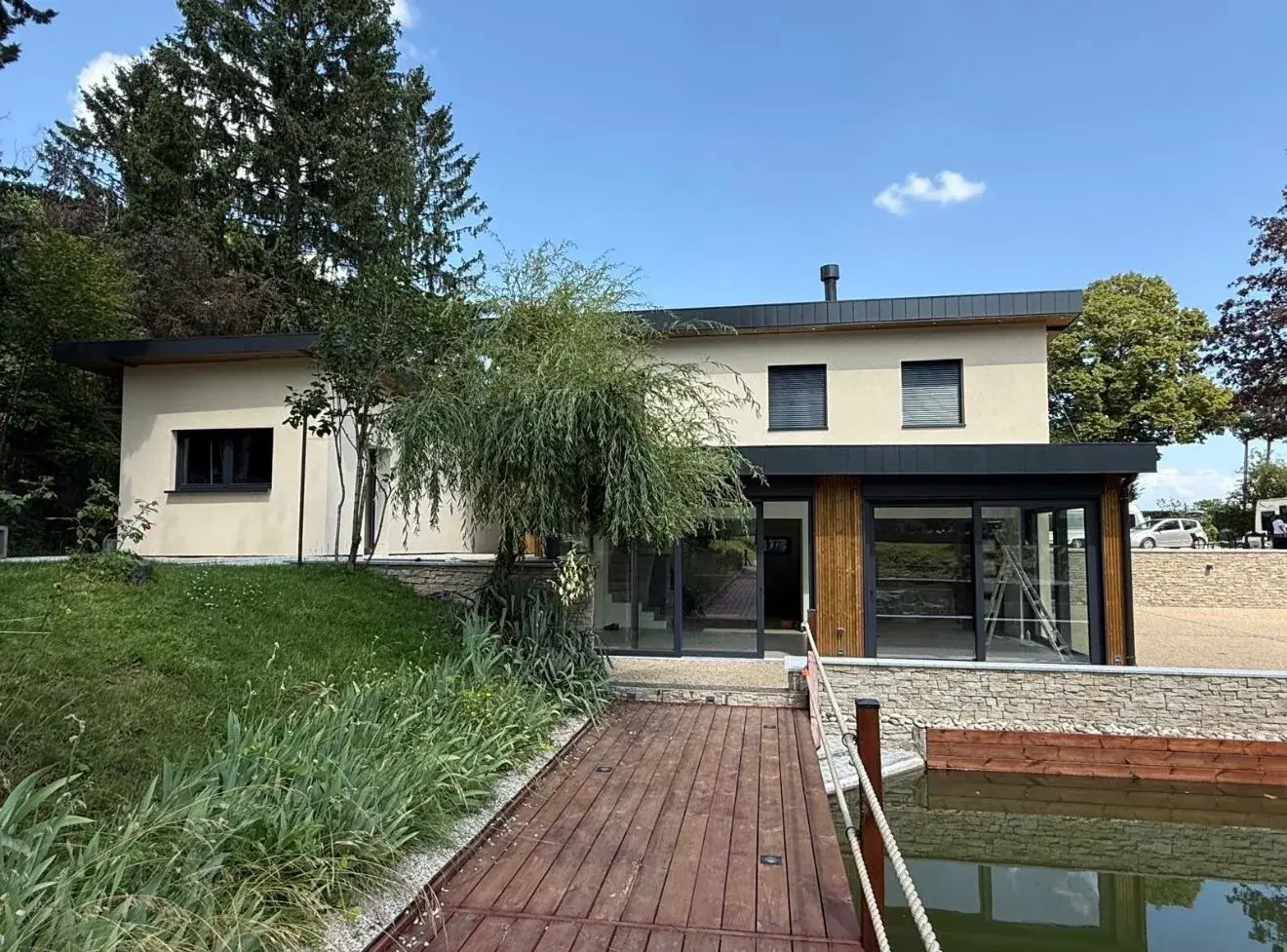 Maison contemporaine à bardage bois et grandes baies vitrées, au bord d'un étang