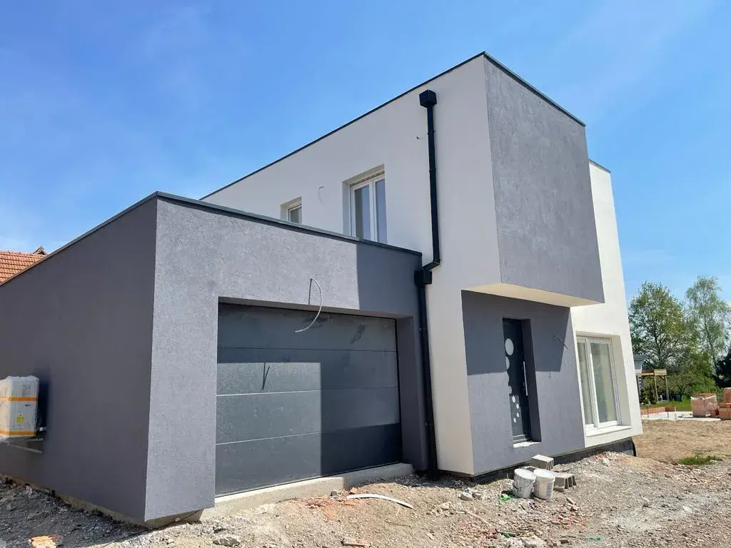 Maison cubique grise et blanche en fin de chantier, menuiseries posées