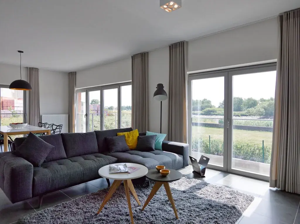 Salon avec trois grandes baies vitrées panoramiques ouvrant sur la campagne