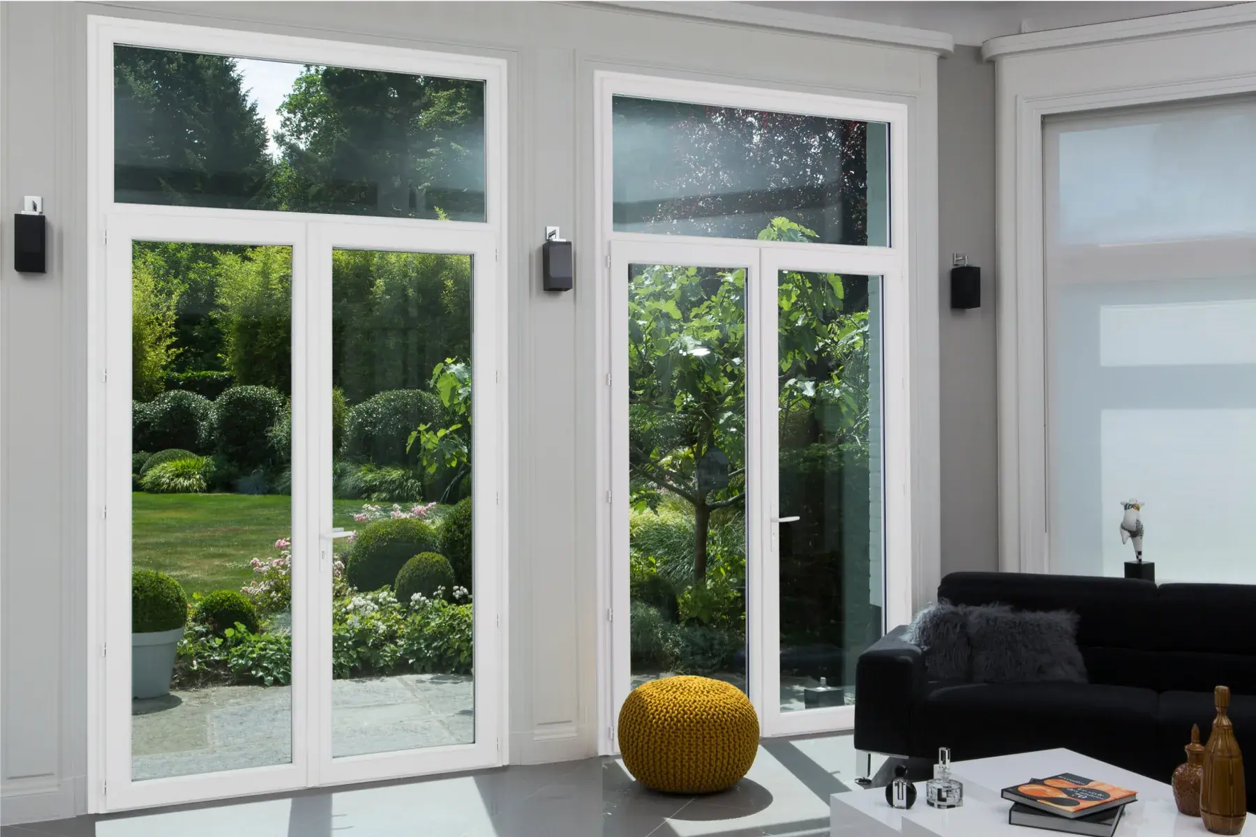 Séjour clair avec deux portes-fenêtres blanches donnant sur un jardin arboré