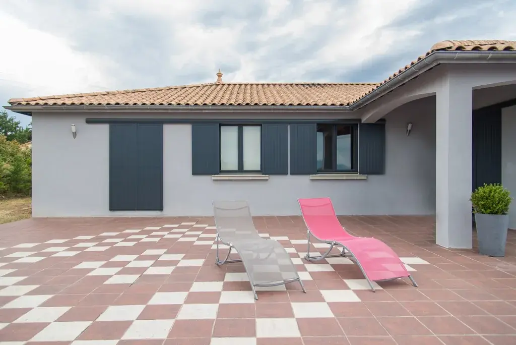 Villa à terrasse carrelée avec volets battants et grandes ouvertures